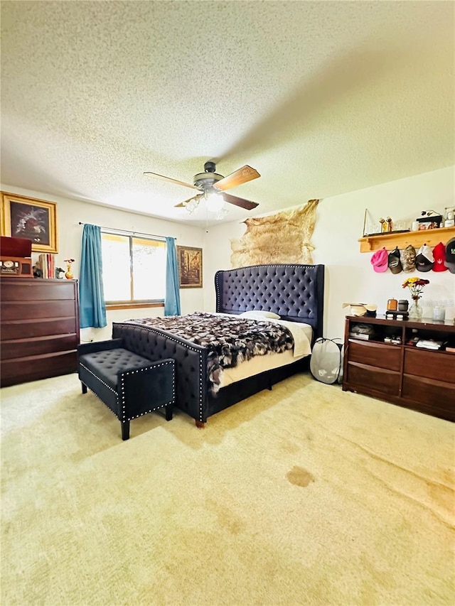 bedroom with ceiling fan, light colored carpet, and a textured ceiling