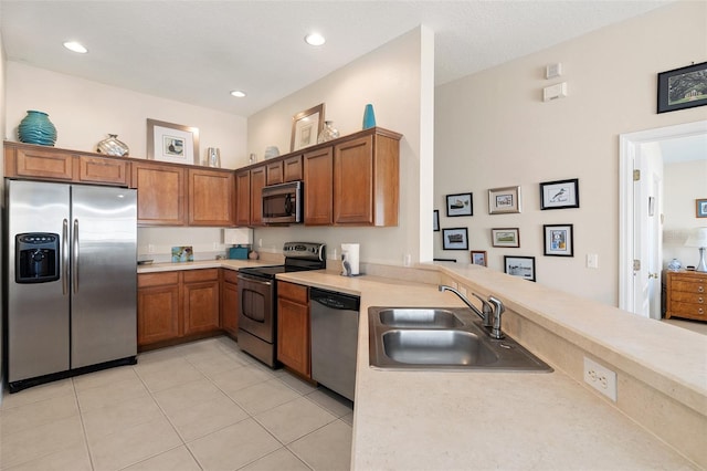 kitchen with appliances with stainless steel finishes, sink, light tile patterned floors, and kitchen peninsula