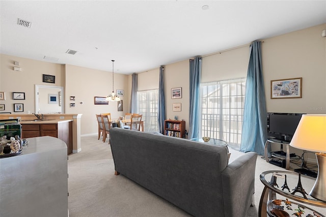 carpeted living room featuring an inviting chandelier and sink