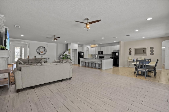 living room with a textured ceiling and ceiling fan