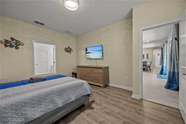 bedroom with light hardwood / wood-style flooring and a textured ceiling