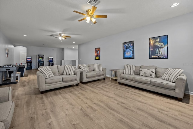 living room with ceiling fan, a textured ceiling, and light hardwood / wood-style floors