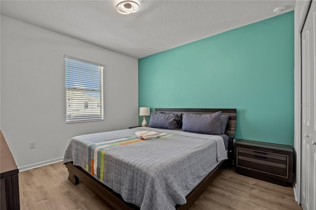 bedroom with a textured ceiling, light wood-type flooring, and a closet