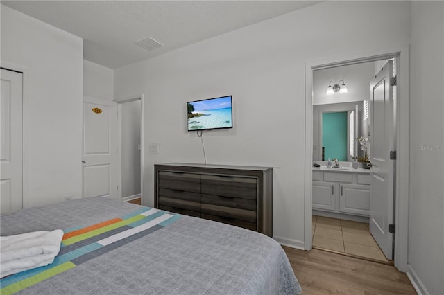 bedroom with sink, connected bathroom, and light hardwood / wood-style floors