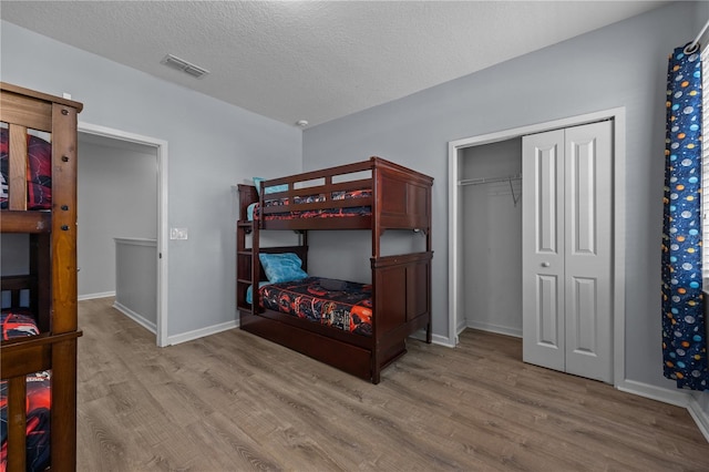 bedroom featuring a closet, a textured ceiling, and light wood-type flooring