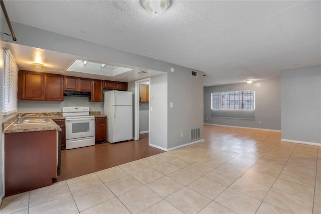 kitchen featuring white appliances, a textured ceiling, sink, light stone counters, and light tile patterned floors