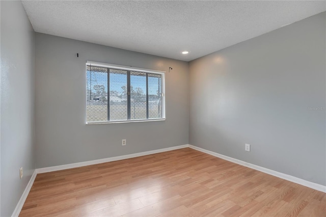 spare room with a textured ceiling and light hardwood / wood-style flooring