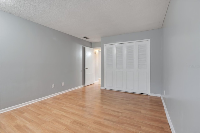 unfurnished bedroom with a closet, light hardwood / wood-style floors, and a textured ceiling