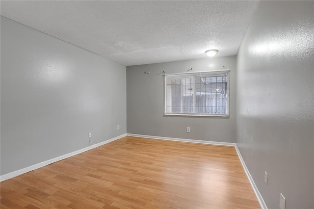 spare room featuring a textured ceiling and light hardwood / wood-style flooring