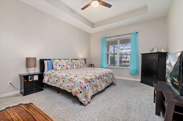 bedroom featuring carpet, ceiling fan, and a raised ceiling