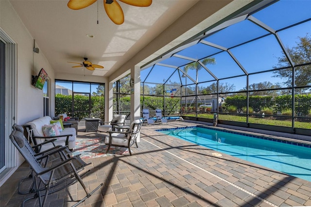 view of swimming pool with a patio area, ceiling fan, an outdoor hangout area, and glass enclosure