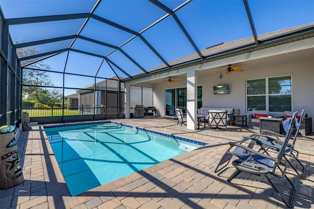 view of swimming pool with ceiling fan, glass enclosure, a patio area, and an outdoor hangout area