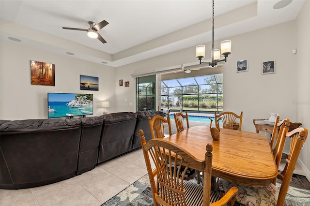 tiled dining room with ceiling fan and a raised ceiling