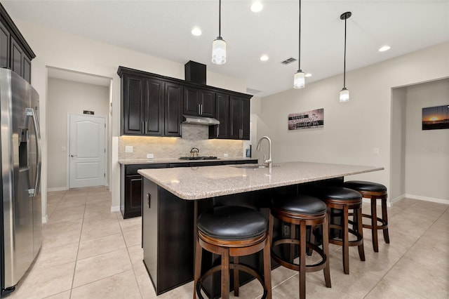 kitchen with an island with sink, appliances with stainless steel finishes, and hanging light fixtures