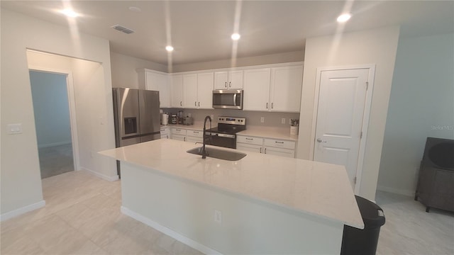 kitchen with white cabinets, appliances with stainless steel finishes, an island with sink, and sink