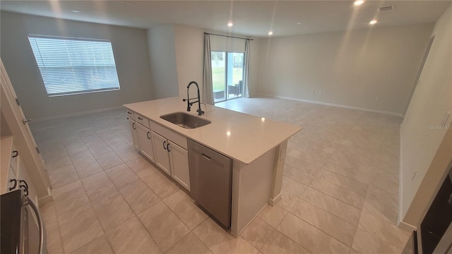 kitchen featuring dishwasher, an island with sink, light tile patterned floors, sink, and white cabinetry