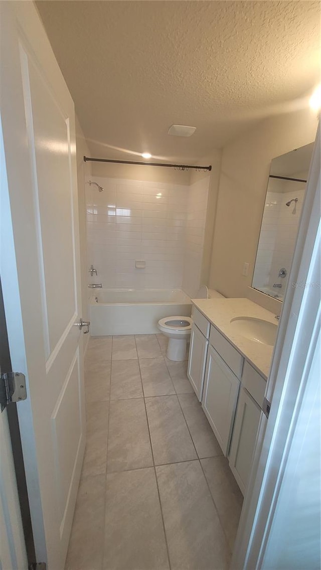 full bathroom featuring tile patterned flooring, toilet, vanity, tiled shower / bath, and a textured ceiling