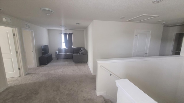 hall with a textured ceiling and light carpet