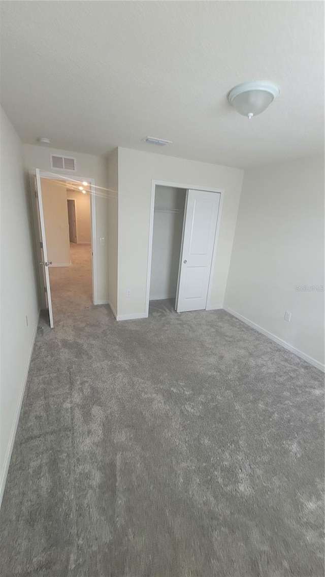 unfurnished bedroom with a closet and dark carpet