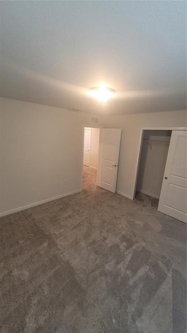 unfurnished bedroom featuring dark carpet, a closet, and a textured ceiling