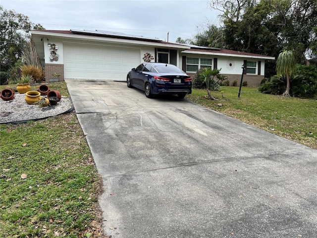 single story home featuring a garage, a front lawn, and solar panels