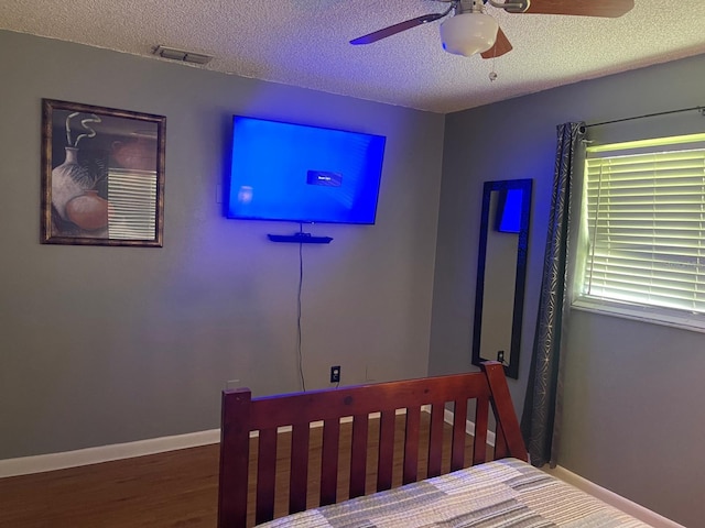 bedroom featuring hardwood / wood-style floors, a textured ceiling, and ceiling fan