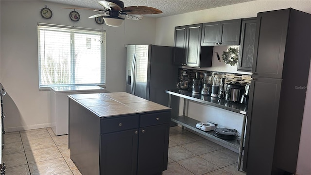 kitchen with stainless steel refrigerator with ice dispenser, plenty of natural light, and a textured ceiling