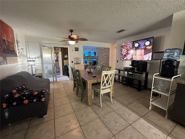 tiled dining space with ceiling fan and a textured ceiling