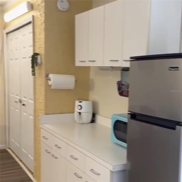 kitchen with stainless steel refrigerator and white cabinets