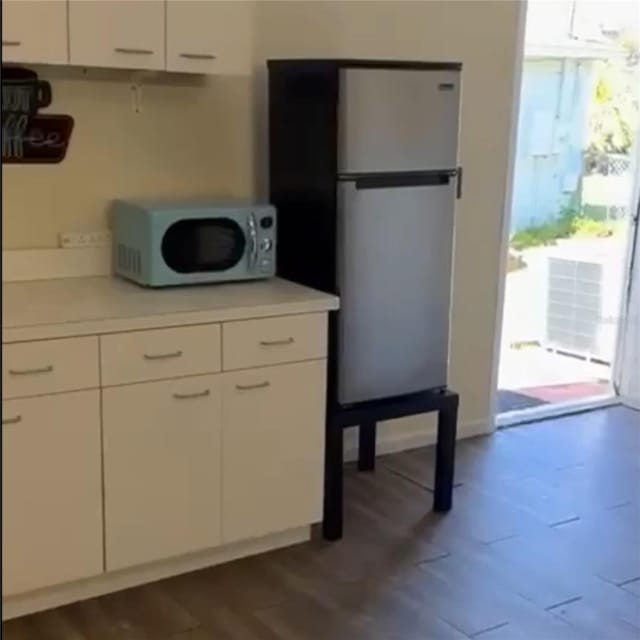 kitchen with stainless steel fridge and white cabinets