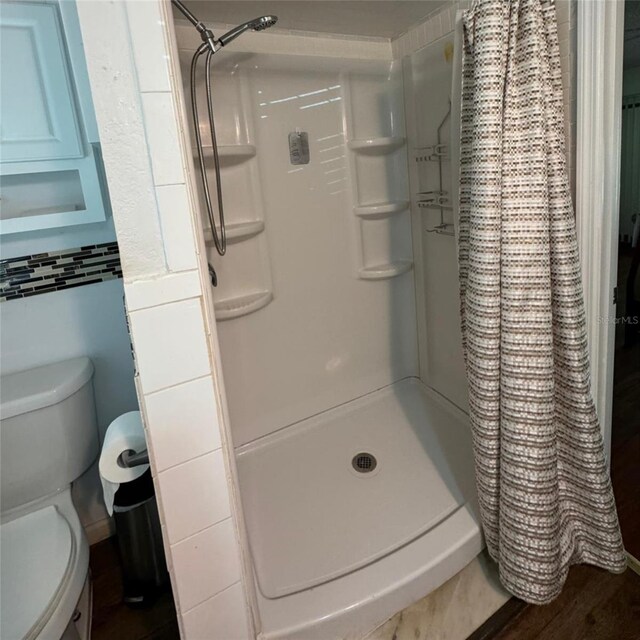 bathroom featuring toilet, hardwood / wood-style floors, and a shower with curtain