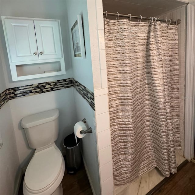 bathroom with hardwood / wood-style flooring, toilet, tile walls, and a shower with curtain