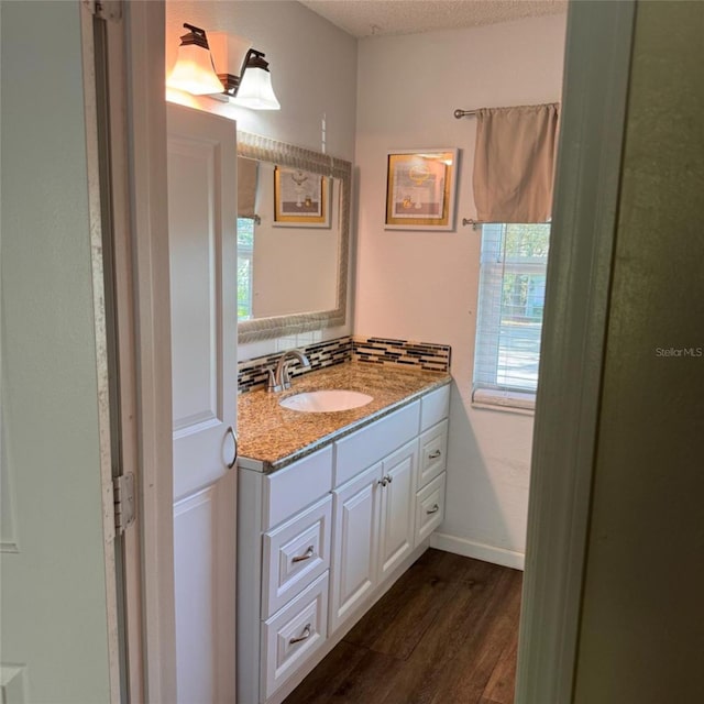 bathroom featuring vanity, backsplash, wood-type flooring, and a textured ceiling