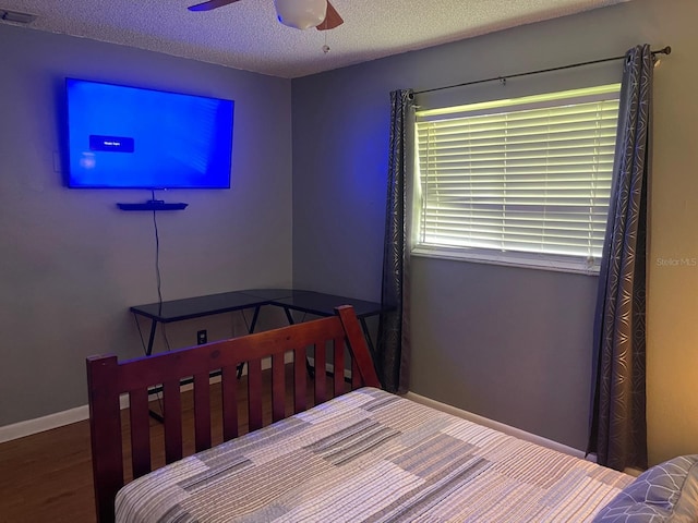 bedroom with hardwood / wood-style flooring, a textured ceiling, and ceiling fan