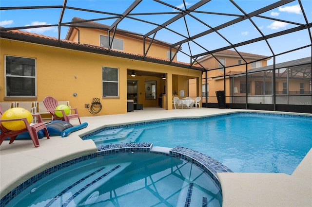 view of pool with a lanai, ceiling fan, an in ground hot tub, and a patio area