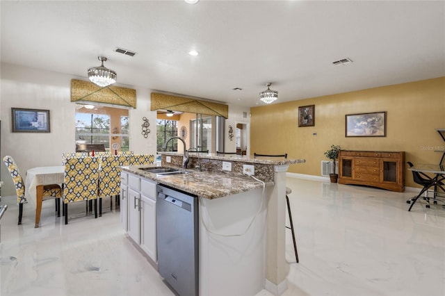 kitchen featuring sink, dishwasher, a kitchen island with sink, and light stone counters