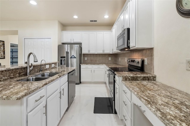 kitchen featuring white cabinets, appliances with stainless steel finishes, decorative backsplash, and sink