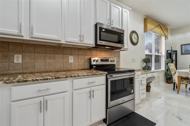 kitchen with appliances with stainless steel finishes, white cabinets, dark stone countertops, and decorative backsplash