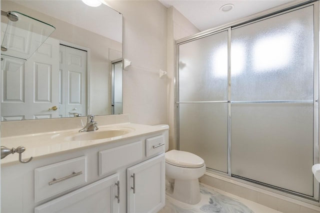 bathroom featuring toilet, a shower with shower door, and vanity