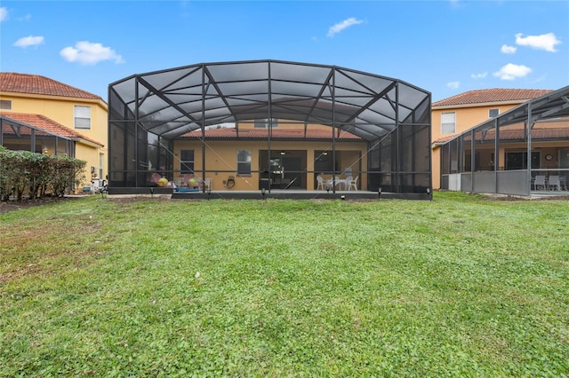 back of house featuring glass enclosure and a lawn