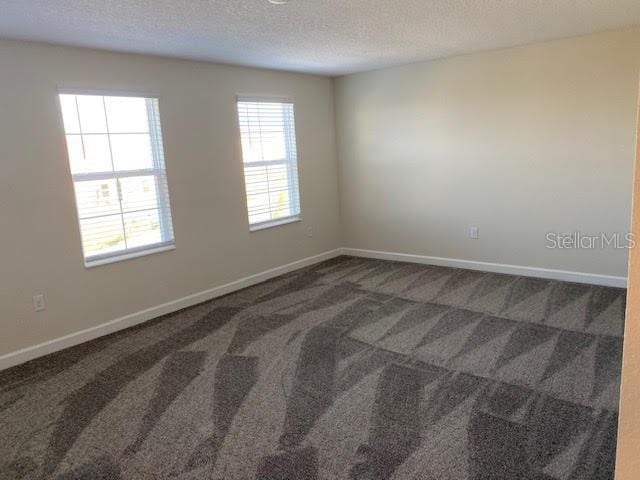 carpeted empty room featuring a textured ceiling