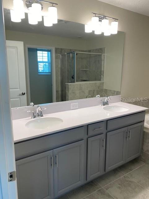 bathroom featuring plus walk in shower, tile patterned flooring, vanity, and a notable chandelier