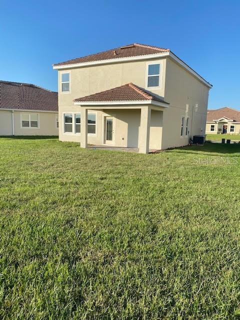 rear view of house with central air condition unit and a yard