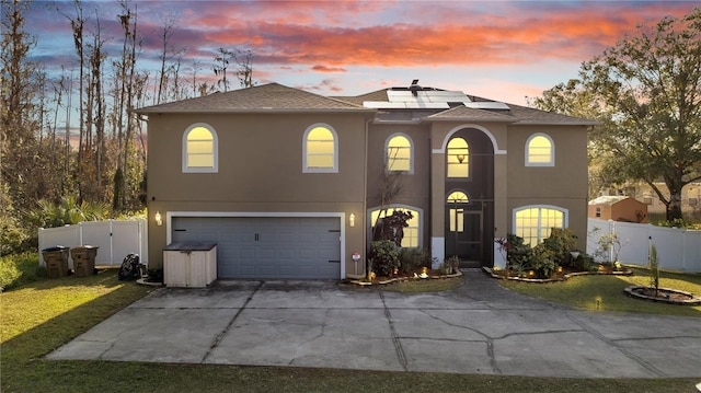 view of front facade with a lawn, solar panels, and a garage