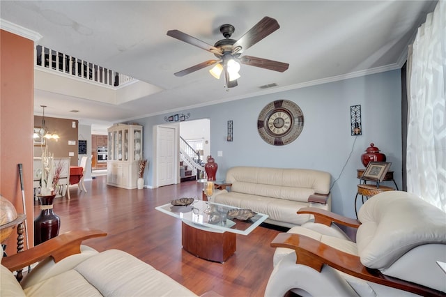 living room with ornamental molding, dark wood-type flooring, and ceiling fan with notable chandelier