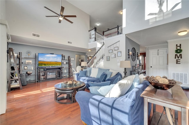 living room featuring a high ceiling, hardwood / wood-style floors, ceiling fan, and ornamental molding