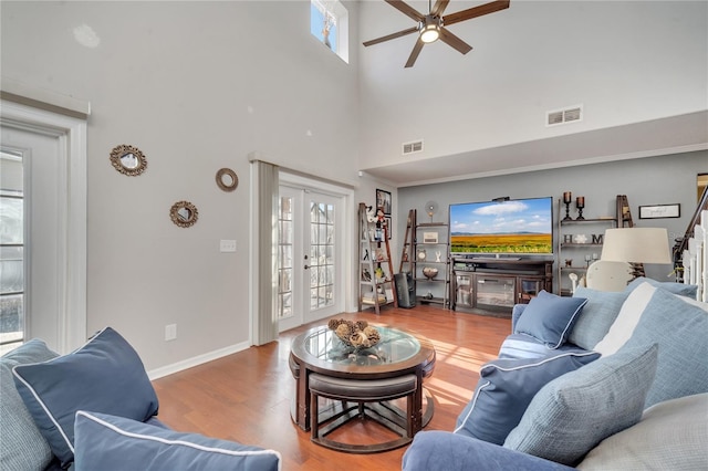 living room with a high ceiling, ceiling fan, and wood-type flooring