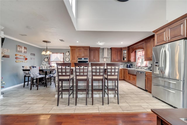 kitchen with stainless steel appliances, hanging light fixtures, a notable chandelier, wall chimney exhaust hood, and sink