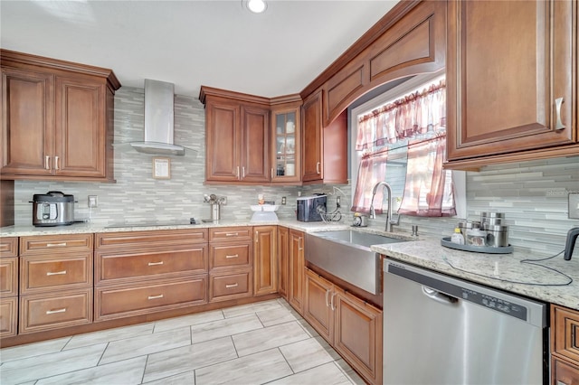 kitchen featuring light stone counters, stainless steel dishwasher, wall chimney exhaust hood, backsplash, and sink