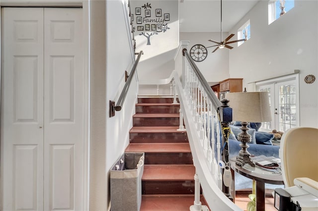 staircase featuring ceiling fan, french doors, and a high ceiling